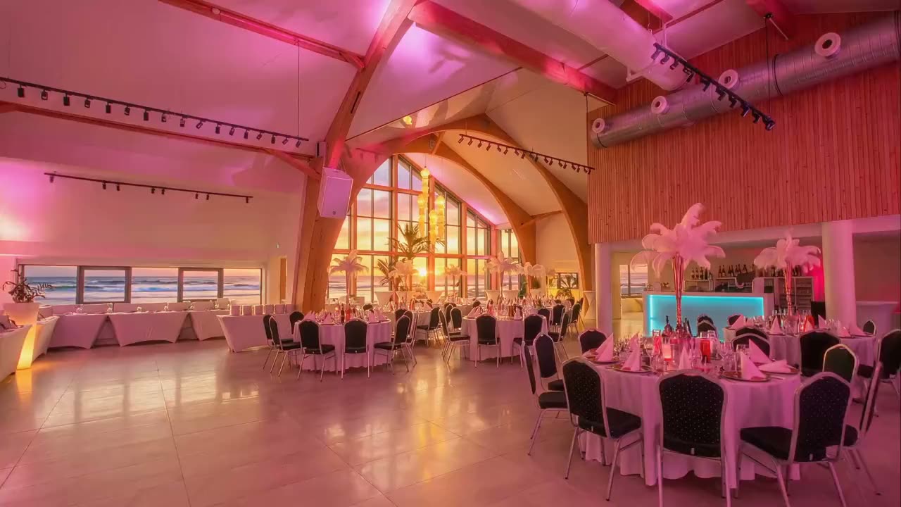 Sala bankietowa MUDO przygotowana na przyjęcie: okrągłe stoły, kwiaty i okna na morze