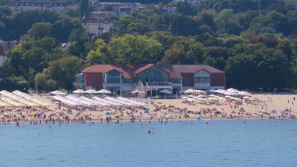 Budynek MUDO i plaża z parasolami widziane z drona od strony morza