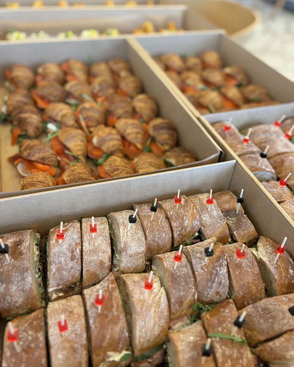 Mini sandwicze z bagietki i mini croissanty z łososiem w kartonach cateringowych