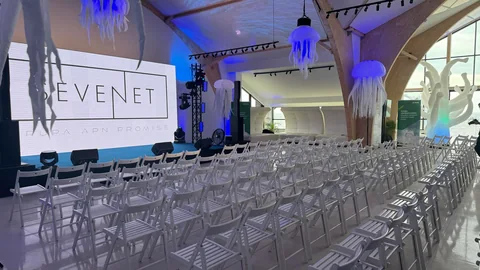 Scena z ekranem LED i niebieskim oświetleniem podczas konferencji firmowej w sali