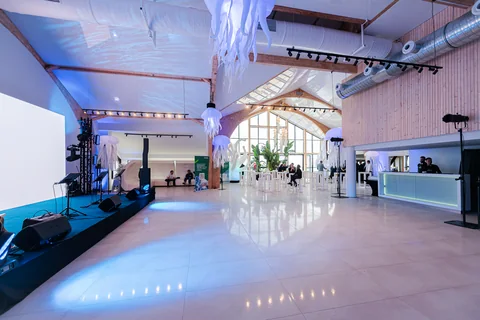 Sala eventowa ze sceną, barem i stolikami koktajlowymi dla gości firmowego wydarzenia
