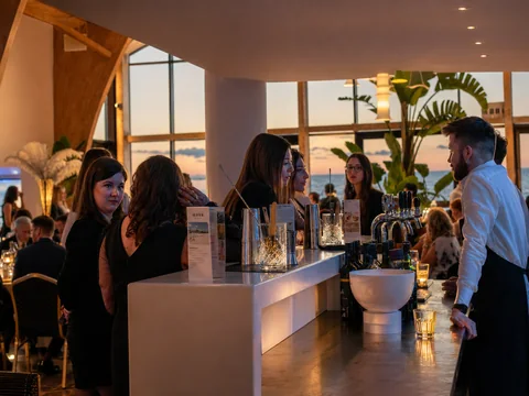 Barman obsługuje gości przy barze w sali eventowej podczas zachodu słońca