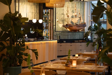 Bar restauracji z modelem żaglowca i nakrytymi stolikami w wieczornym świetle