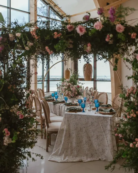 Stół weselny pod łukiem z kwiatów w sali restauracyjnej MUDO, za oknami morze