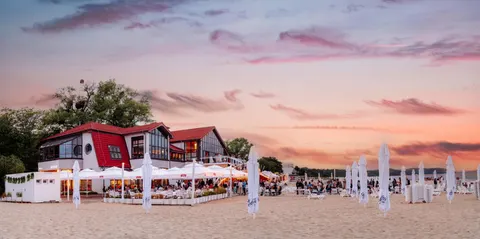 Budynek MUDO i plaża z parasolami o zachodzie słońca