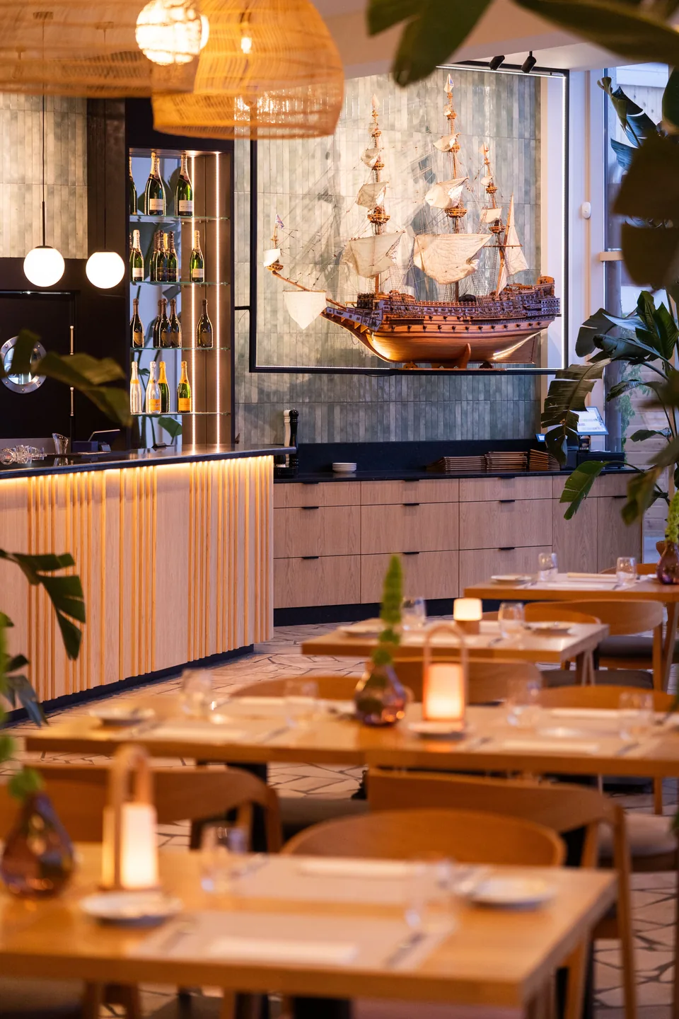 Nakryte stoliki ze świecami przy barze z modelem żaglowca w sali restauracyjnej