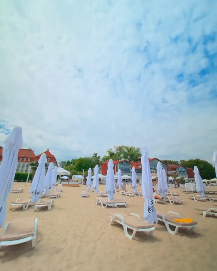 Leżaki z materacami pod parasolami na plaży MUDO