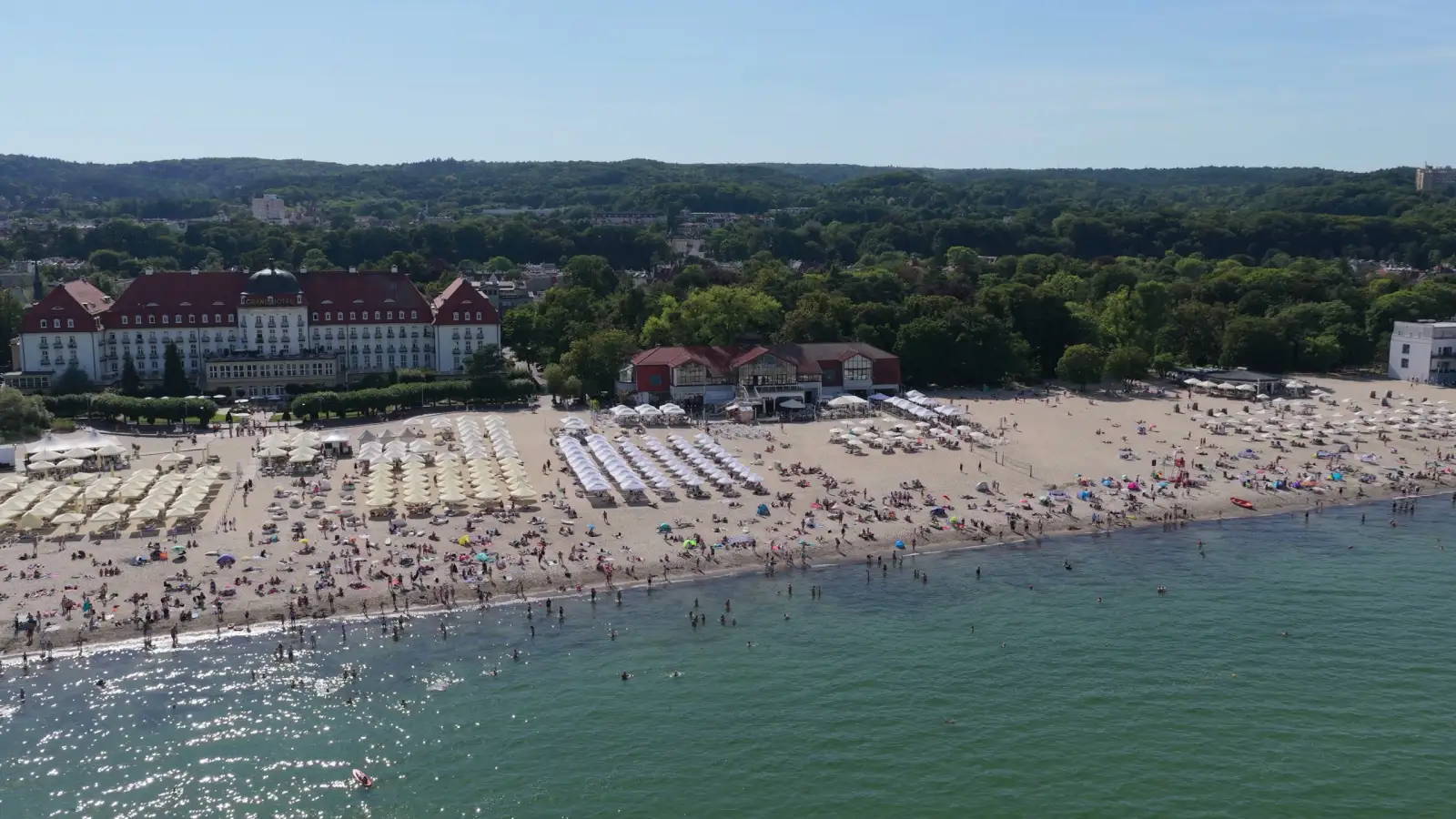 Widok z drona: plaża w Sopocie przed budynkiem MUDO, w oknach znaku MUDO woda